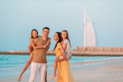 Portrait of friends standing at sea against clear sky