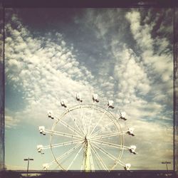 Low angle view of ferris wheel against cloudy sky