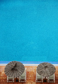 High angle view of thatched roof with deck chairs at poolside