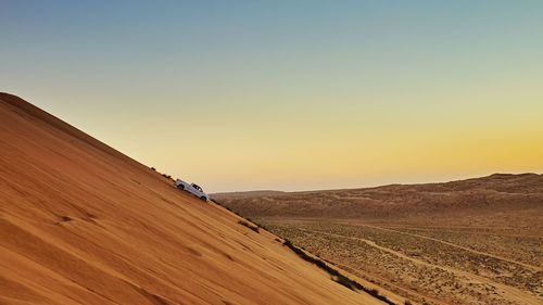 Scenic view of desert against clear sky during sunset
