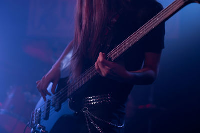 Midsection of woman playing guitar in concert