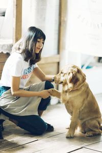 Young woman with dog crouching on floor