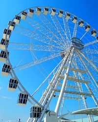 Low angle view of ferris wheel against blue sky