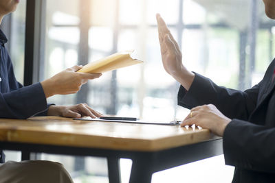 Midsection of man holding hands on table