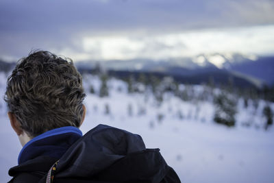 Rear view of boy with snow against sky