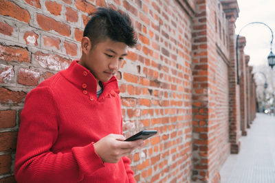 Mid adult man looking at camera while standing against wall