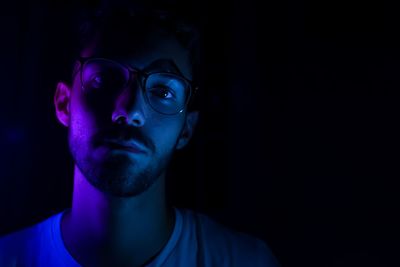 Portrait of young man with illuminated light in darkroom