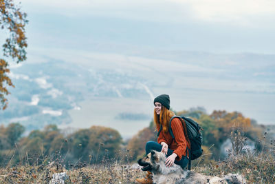 Woman sitting on land against sky