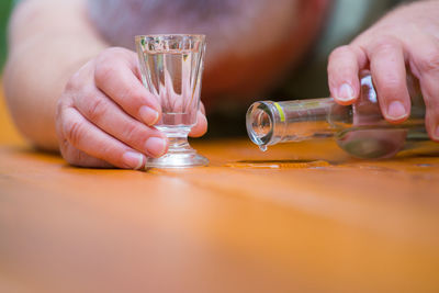 Cropped hands holding drink on wooden table