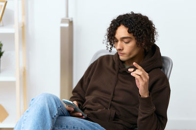 Young man using phone while sitting on chair