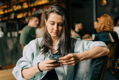 Hipster young woman reading text message on mobile phone at the cafe. person