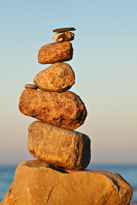 Stack of stones on rock against sky