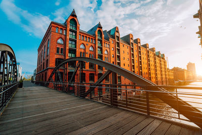 Footbridge amidst buildings in city against sky