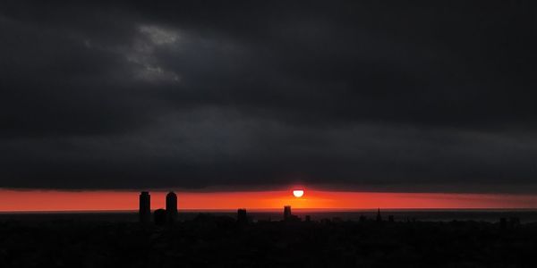 Silhouette landscape against dramatic sky during sunset