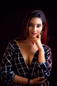 Portrait of young woman sitting against black background