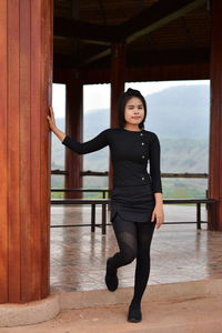 Portrait of young woman standing by column at observation point