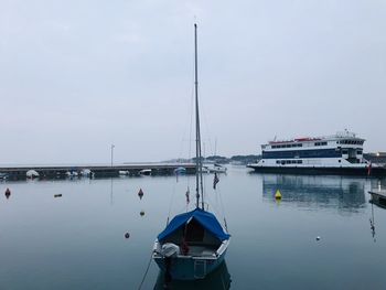 Sailboats moored at harbor against sky