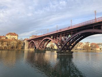 Arch bridge over river in city against sky