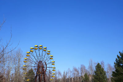 Low angle view of ferris wheel against clear blue sky