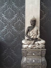 Buddha statue on cabinet by wall