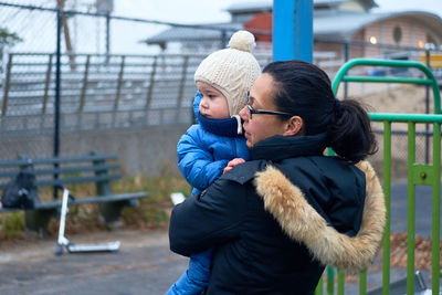 Mom carrying a toddler on the playground