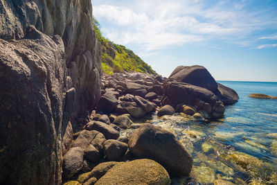 Rock formation on beach against sky