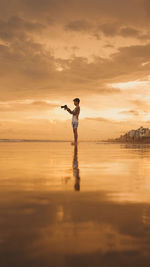 Full length of man standing at beach during sunset