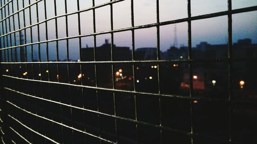 Illuminated fence against sky