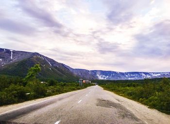 Road leading towards mountains against sky