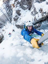 Full length from above of mountaineer ice-climbing with snow