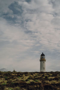 Lighthouse on landscape against sky