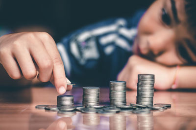 Close-up of boy stacking coins on table