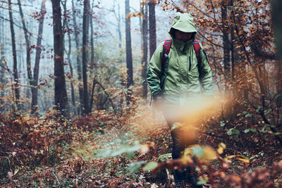 Woman with backpack wandering around a forest on autumn cold day