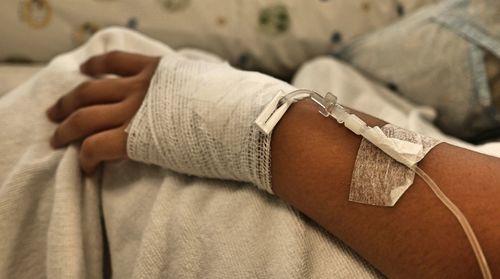 Close-up of hand with iv drip on bed
