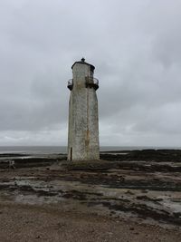 Lighthouse on field against sky
