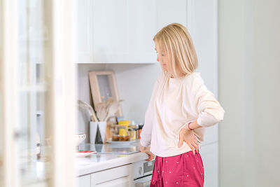 Side view of woman standing at home