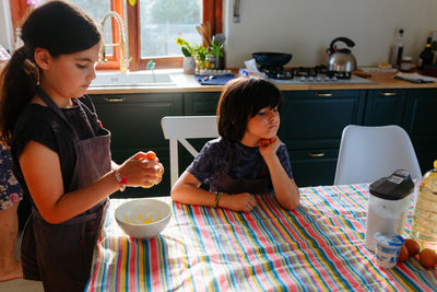 Two girls wearing grey aprons preparing cake in the kitchen at home