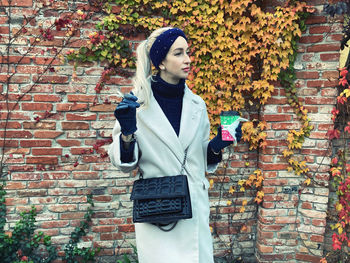 Beautiful young woman standing against brick wall