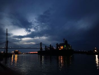 View of suspension bridge over river against cloudy sky