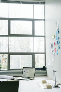 Laptop computer and wind turbine models on desk in office