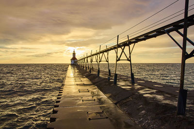Pier over sea against sky during sunset