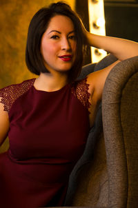 Portrait of smiling beautiful young woman sitting on sofa at home