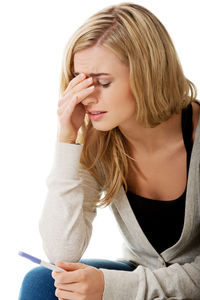 Woman holding equipment during pregnancy test against white background