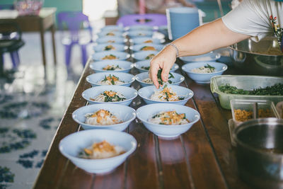 Cropped hand of person preparing food on table in restaurant