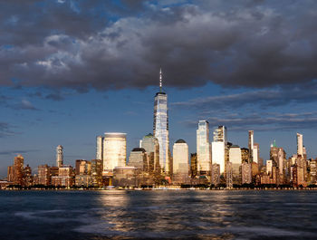 City at waterfront against cloudy sky