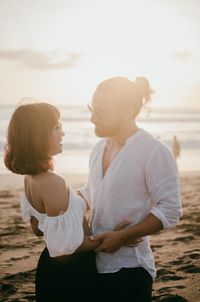 Rear view of friends enjoying at beach against sky