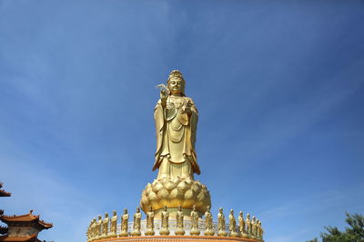 Low angle view of statue against blue sky and building