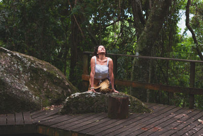 Portrait of young woman standing against trees