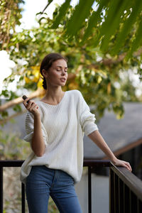 Portrait of young woman standing against trees