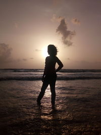 Silhouette man standing on beach against sky during sunset